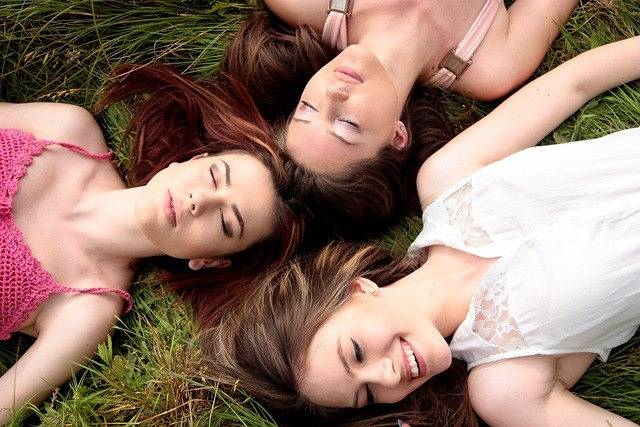 Frauen entspannen im Gras mit geschlossenen Augen – Sehnsucht nach Flusskreuzfahrt